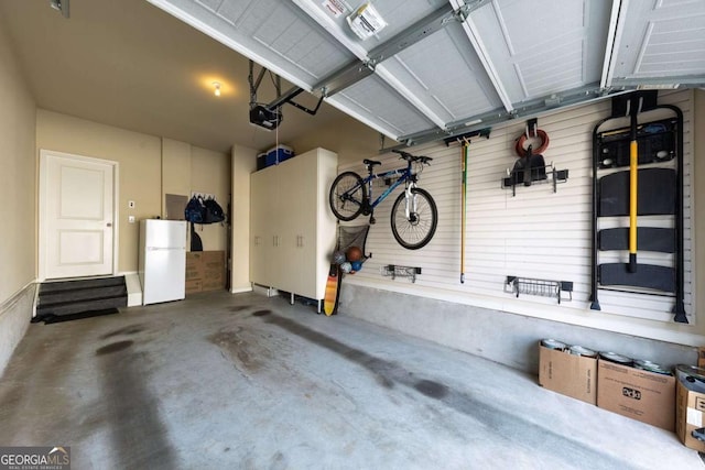 garage featuring freestanding refrigerator and a garage door opener