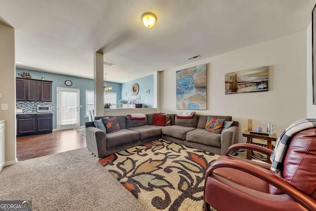 living area with a chandelier, dark wood-style flooring, dark carpet, and visible vents