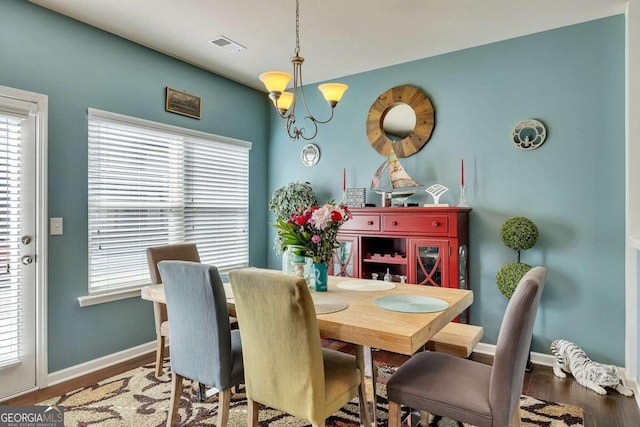 dining area with visible vents, a notable chandelier, baseboards, and wood finished floors