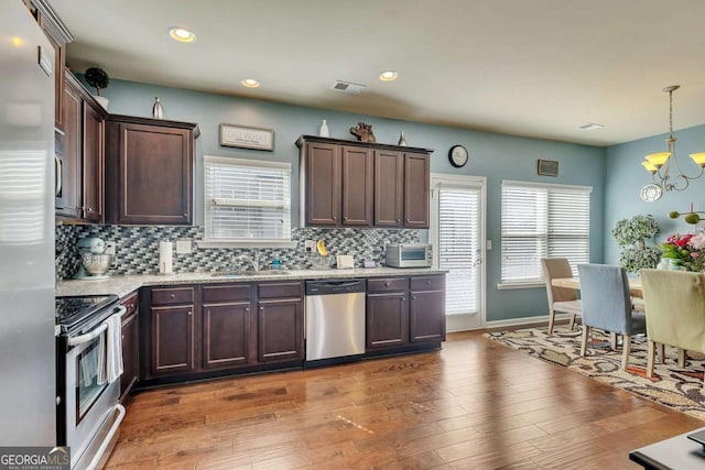 kitchen with hanging light fixtures, appliances with stainless steel finishes, a sink, and decorative backsplash