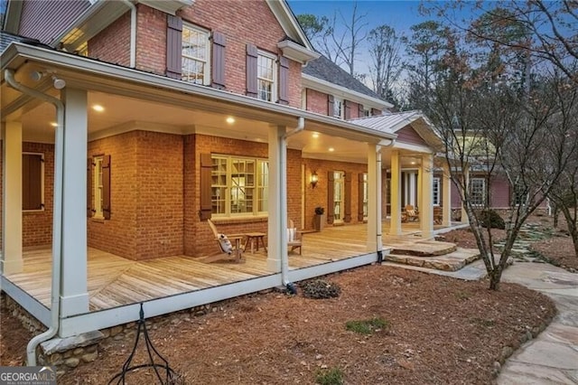 property exterior at dusk with covered porch and brick siding