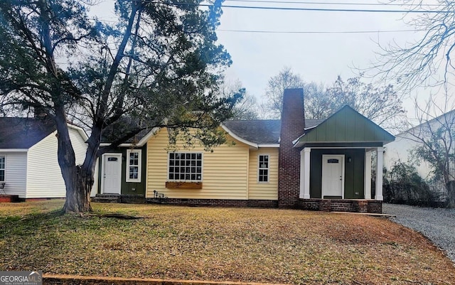 view of front facade featuring entry steps, a chimney, roof with shingles, a front lawn, and board and batten siding