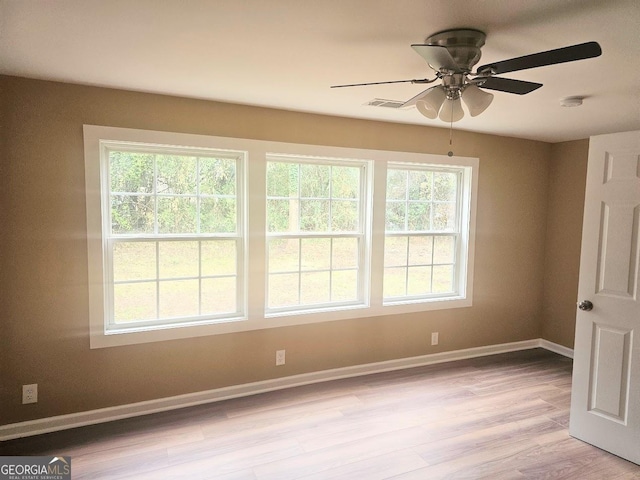 empty room featuring light wood-type flooring, ceiling fan, visible vents, and baseboards