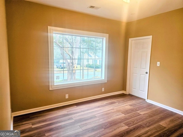 empty room featuring visible vents, baseboards, and wood finished floors