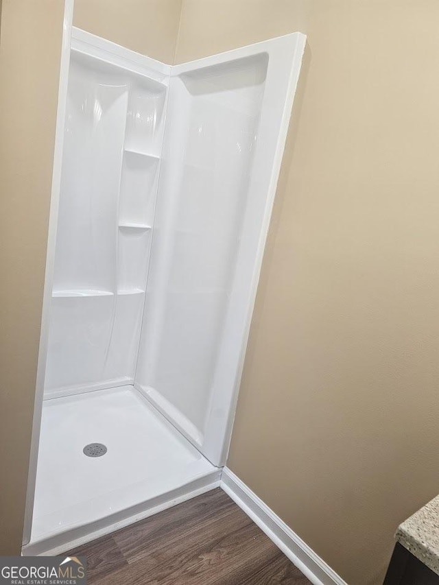 bathroom featuring a shower, wood finished floors, and baseboards