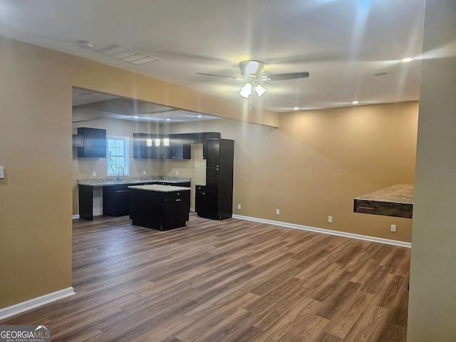 kitchen with a center island, baseboards, light countertops, and dark cabinetry