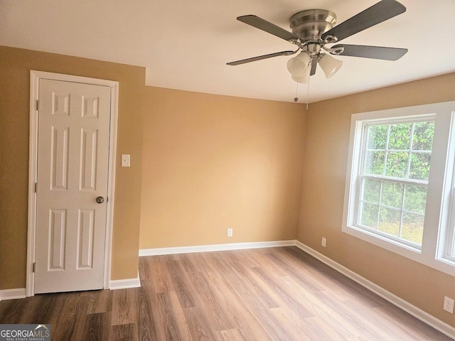 unfurnished room with ceiling fan, light wood-type flooring, and baseboards