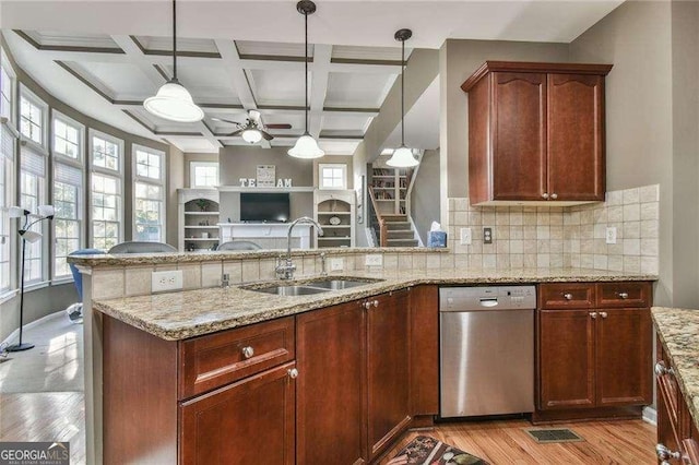 kitchen with coffered ceiling, dishwasher, light stone counters, pendant lighting, and a sink