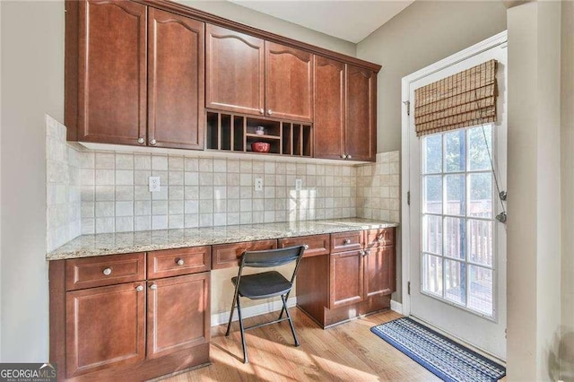 kitchen featuring tasteful backsplash, light stone counters, plenty of natural light, and light wood-style floors