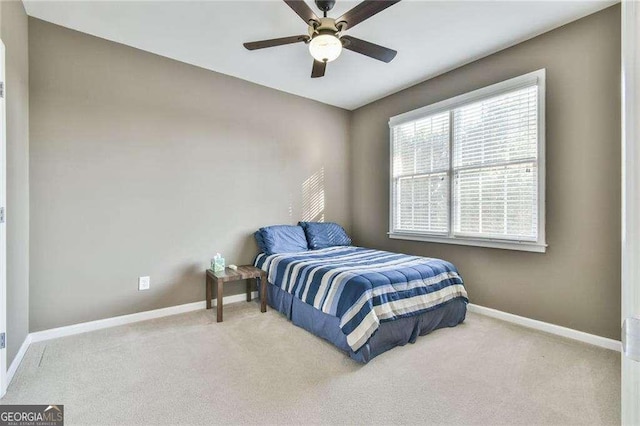 bedroom featuring light carpet, a ceiling fan, and baseboards