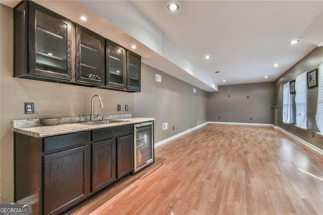 bar with recessed lighting, light wood-style flooring, a sink, beverage cooler, and baseboards