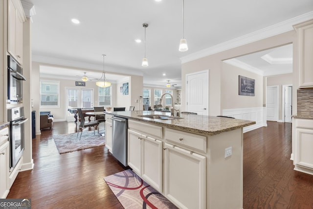 kitchen with pendant lighting, a sink, an island with sink, and light stone countertops