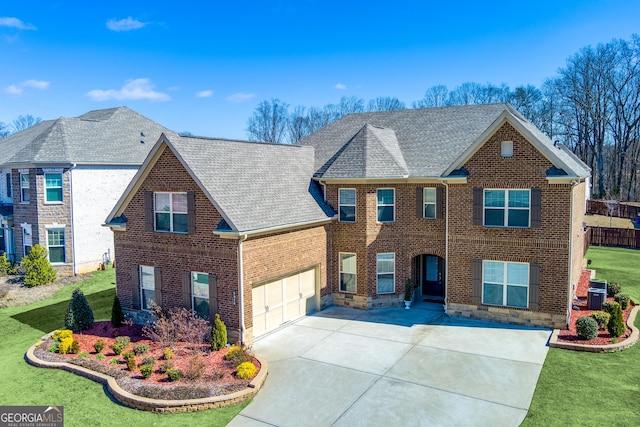 view of front facade with driveway, a front yard, a shingled roof, a garage, and brick siding