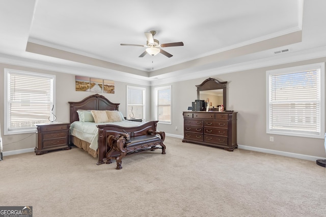 bedroom featuring light carpet, a tray ceiling, baseboards, and crown molding