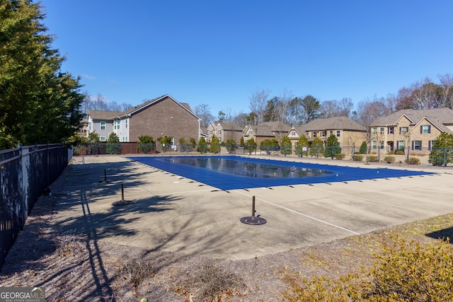 community pool with a patio area, a residential view, and fence