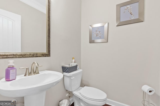 bathroom with toilet, baseboards, and a sink