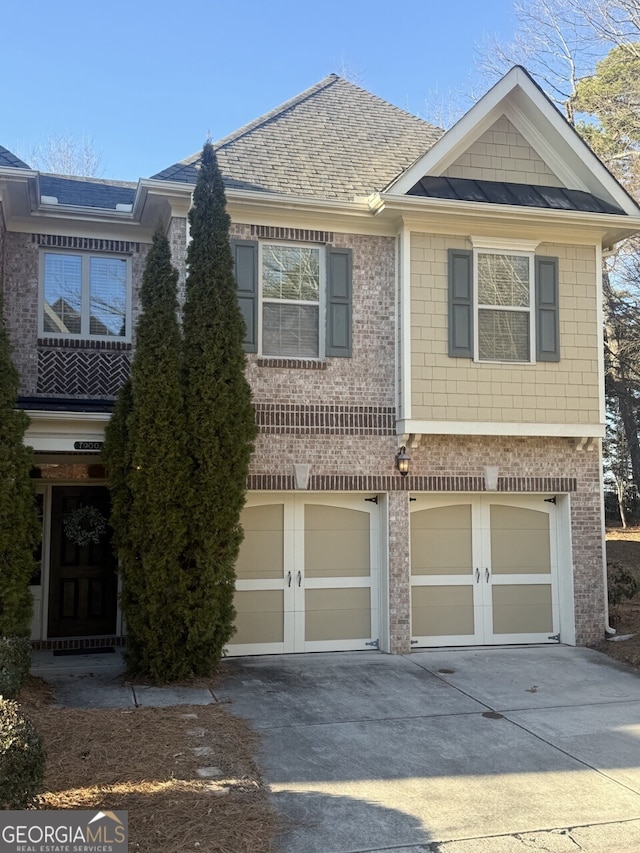 view of property with concrete driveway, metal roof, an attached garage, a standing seam roof, and brick siding