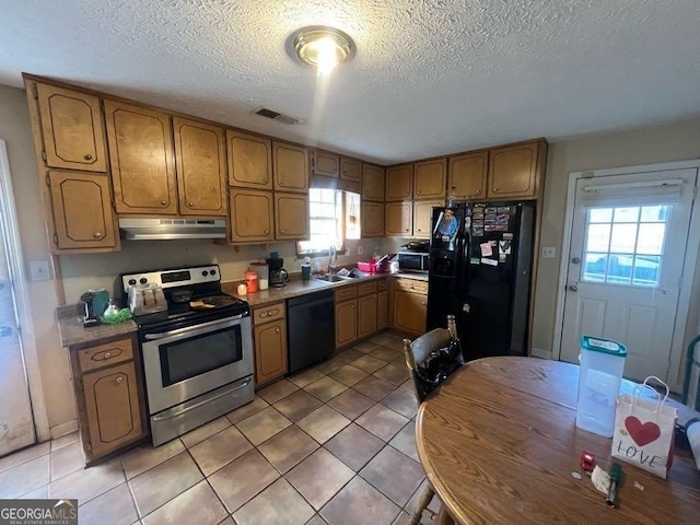 kitchen featuring visible vents, brown cabinetry, under cabinet range hood, black appliances, and a sink