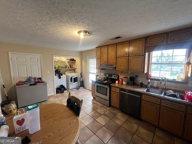 kitchen with black dishwasher, brown cabinetry, stainless steel electric stove, under cabinet range hood, and a sink