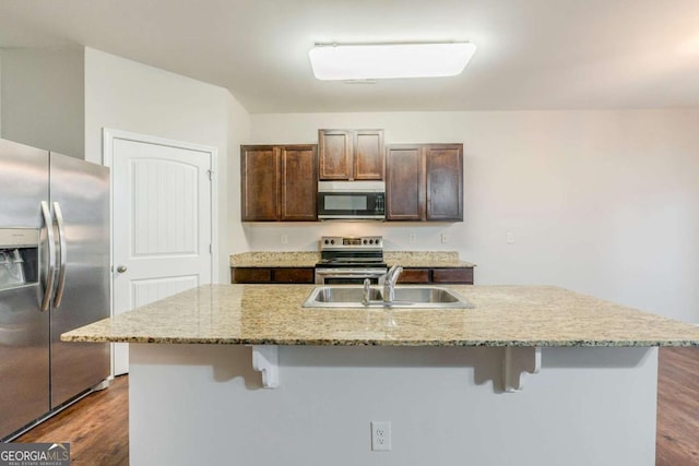 kitchen featuring stainless steel appliances, a kitchen bar, a sink, and a kitchen island with sink