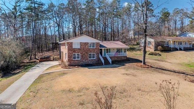 view of front facade with covered porch, driveway, a front lawn, and stairs