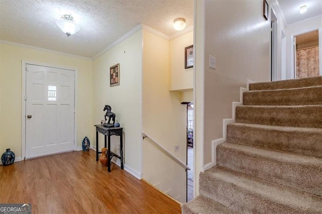 entrance foyer featuring stairs, crown molding, a textured ceiling, and wood finished floors