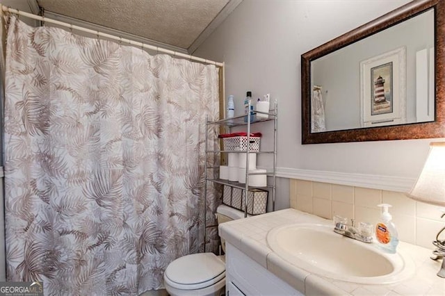 bathroom with ornamental molding, toilet, a textured ceiling, and vanity