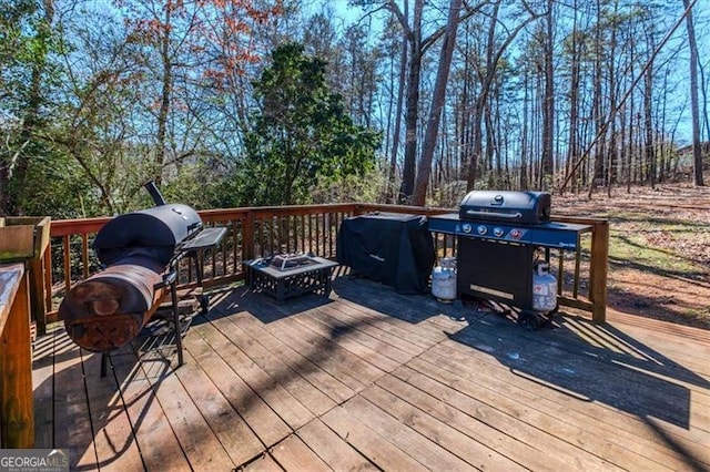 wooden terrace with an outdoor fire pit and a grill