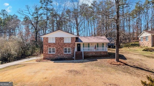 split level home with metal roof, a porch, and a front yard