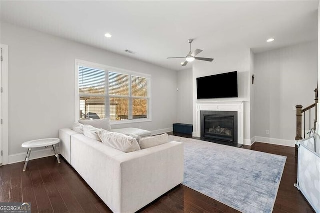 living room with dark wood-type flooring, recessed lighting, a fireplace with flush hearth, and baseboards