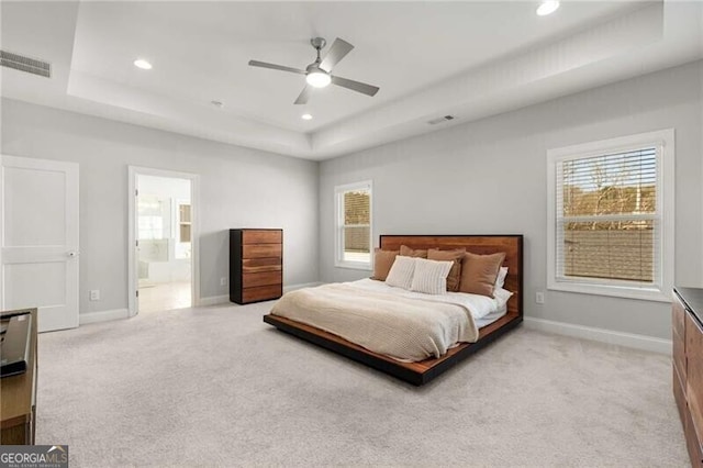 bedroom with a raised ceiling, light carpet, and visible vents