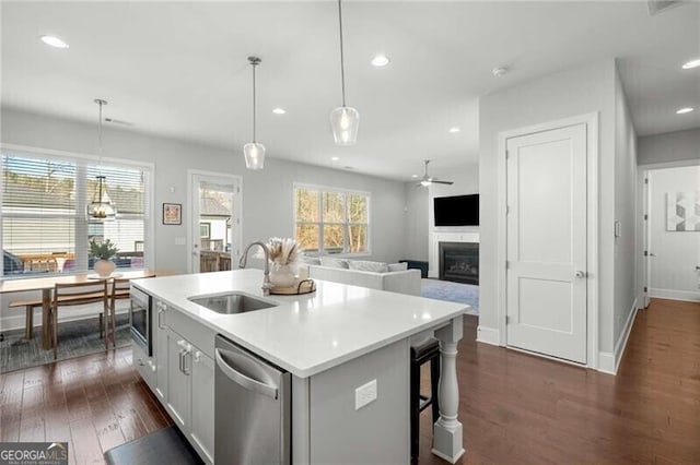 kitchen featuring stainless steel appliances, a sink, light countertops, an island with sink, and pendant lighting