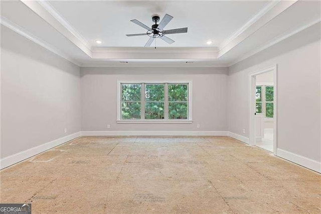 empty room with ornamental molding, a raised ceiling, a ceiling fan, and baseboards