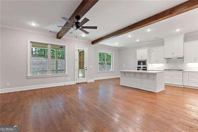 kitchen featuring under cabinet range hood, white cabinetry, open floor plan, and light countertops