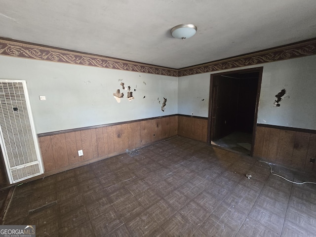 unfurnished room with a wainscoted wall, a heating unit, and wood walls