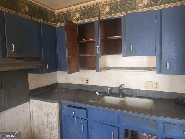 kitchen featuring dark countertops, blue cabinetry, and a sink