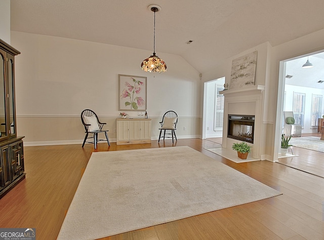 living area featuring vaulted ceiling, wood finished floors, and a multi sided fireplace