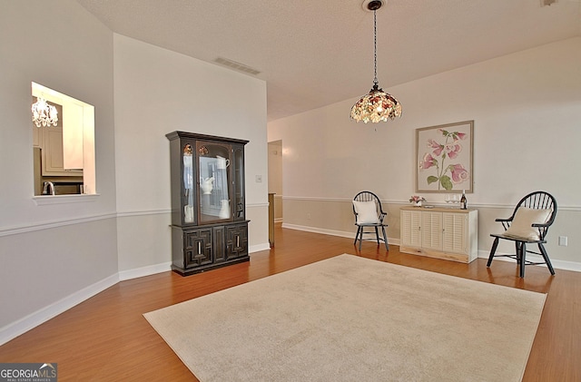 living area with a chandelier, visible vents, baseboards, and wood finished floors