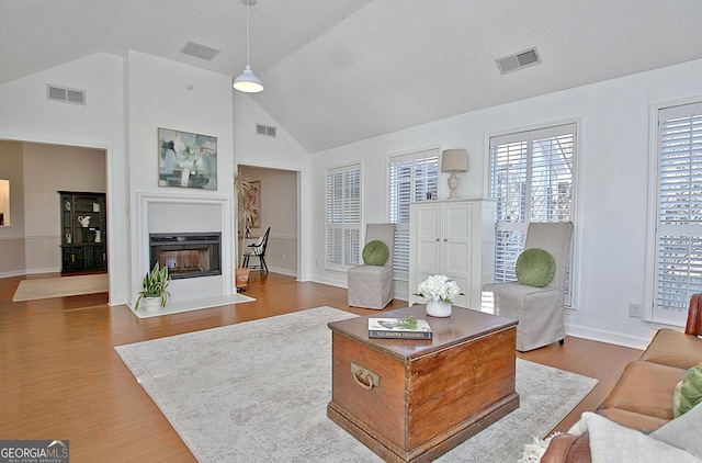 living area featuring wood finished floors, a fireplace with flush hearth, and visible vents