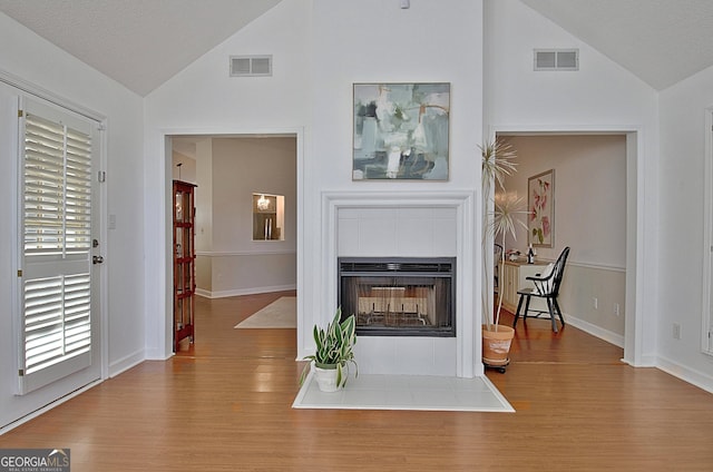 living room featuring vaulted ceiling, a fireplace, and visible vents