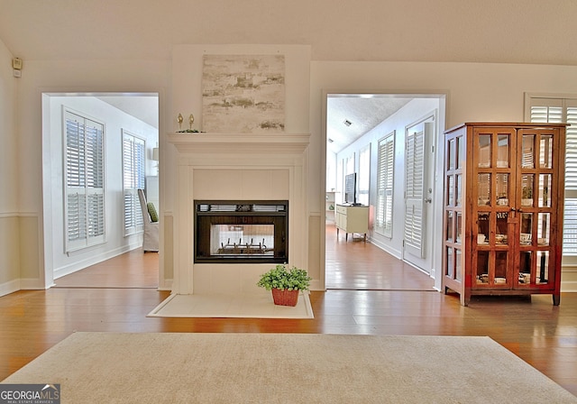 foyer entrance with a tile fireplace, wood finished floors, and baseboards