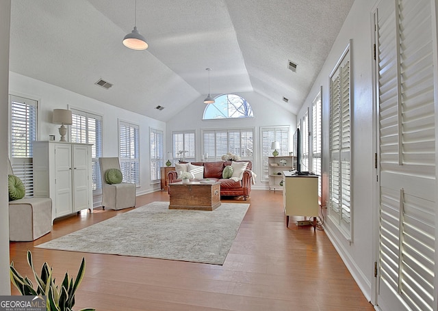 living area with plenty of natural light, visible vents, and wood finished floors