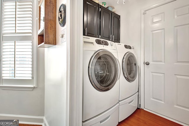 laundry area with baseboards, wood finished floors, cabinet space, and washer and dryer