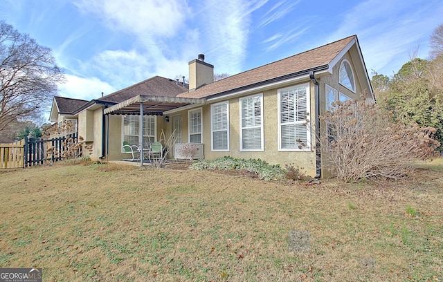 back of house with roof with shingles, a yard, a chimney, stucco siding, and fence