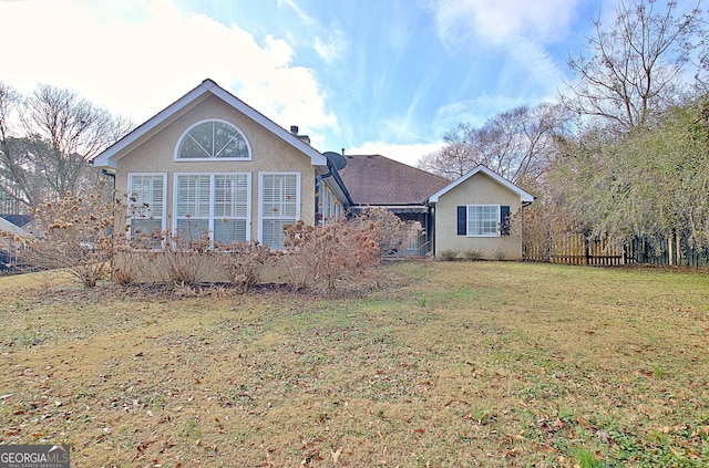 view of front facade with stucco siding, fence, and a front yard