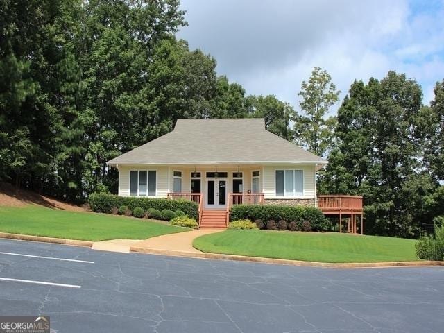 view of front facade featuring uncovered parking, a front lawn, and french doors