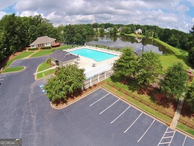 community pool with a water view, fence, and a patio