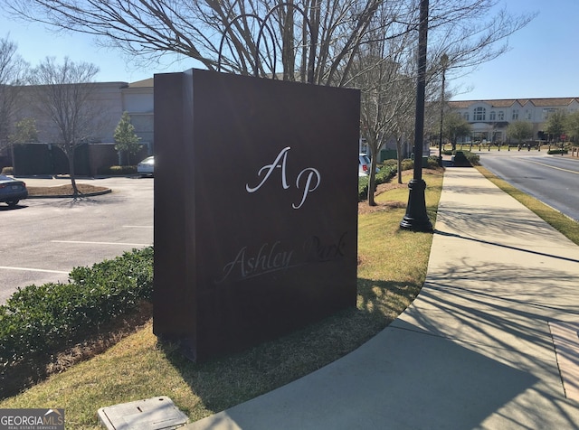 community sign featuring uncovered parking and a residential view