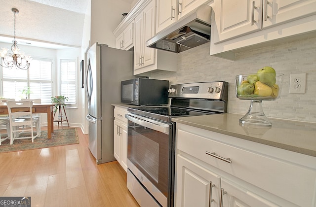 kitchen with pendant lighting, light countertops, appliances with stainless steel finishes, white cabinetry, and under cabinet range hood