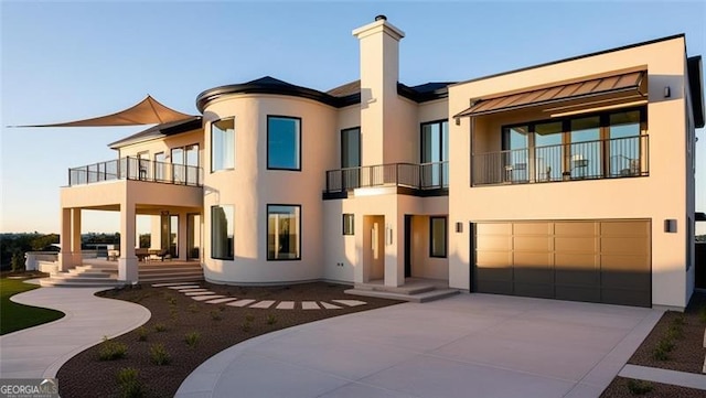 rear view of property with driveway, an attached garage, and stucco siding